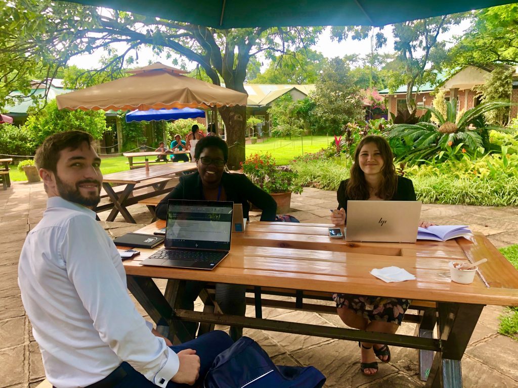 A meetiing between two KOIS employees and a UNDP representative in Malawi. The team sits at a wooden table.